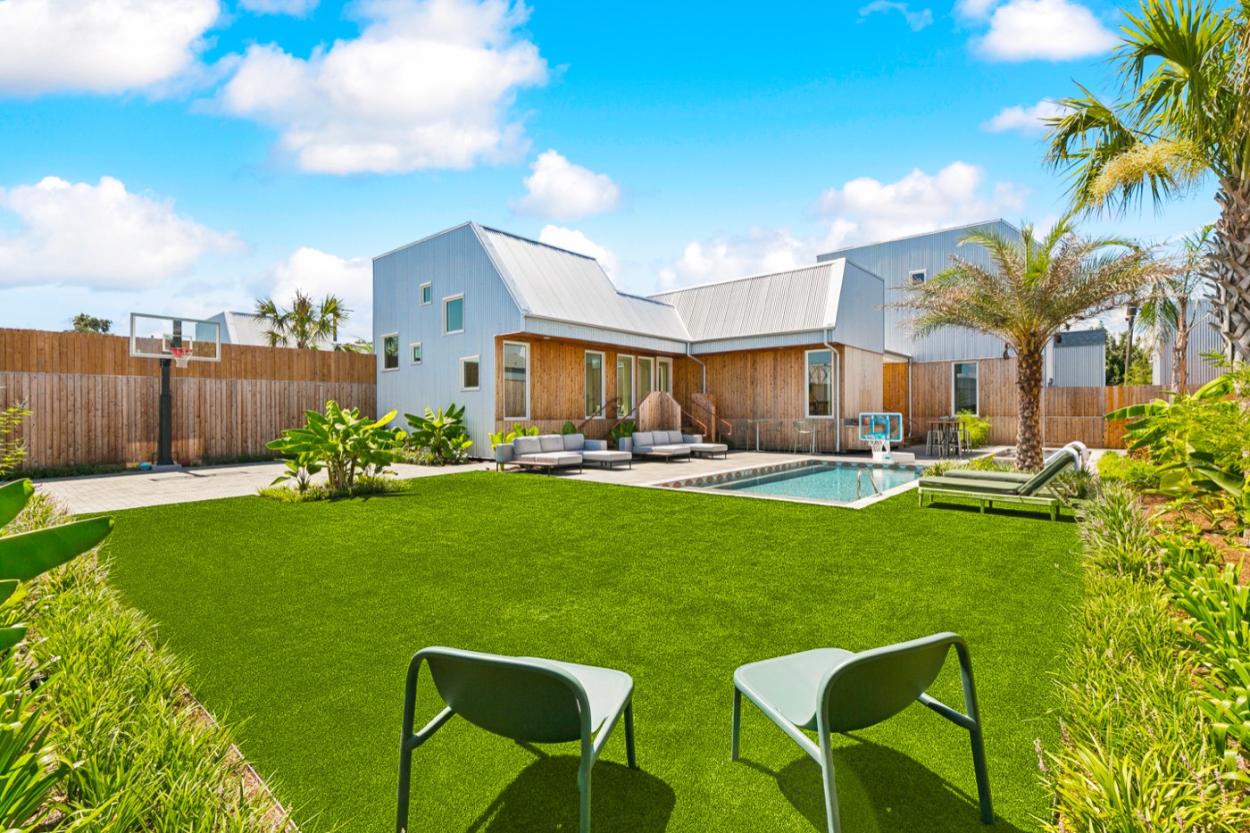 Big private lawn with cornhole, villa and pool behind, at a New Orleans group property