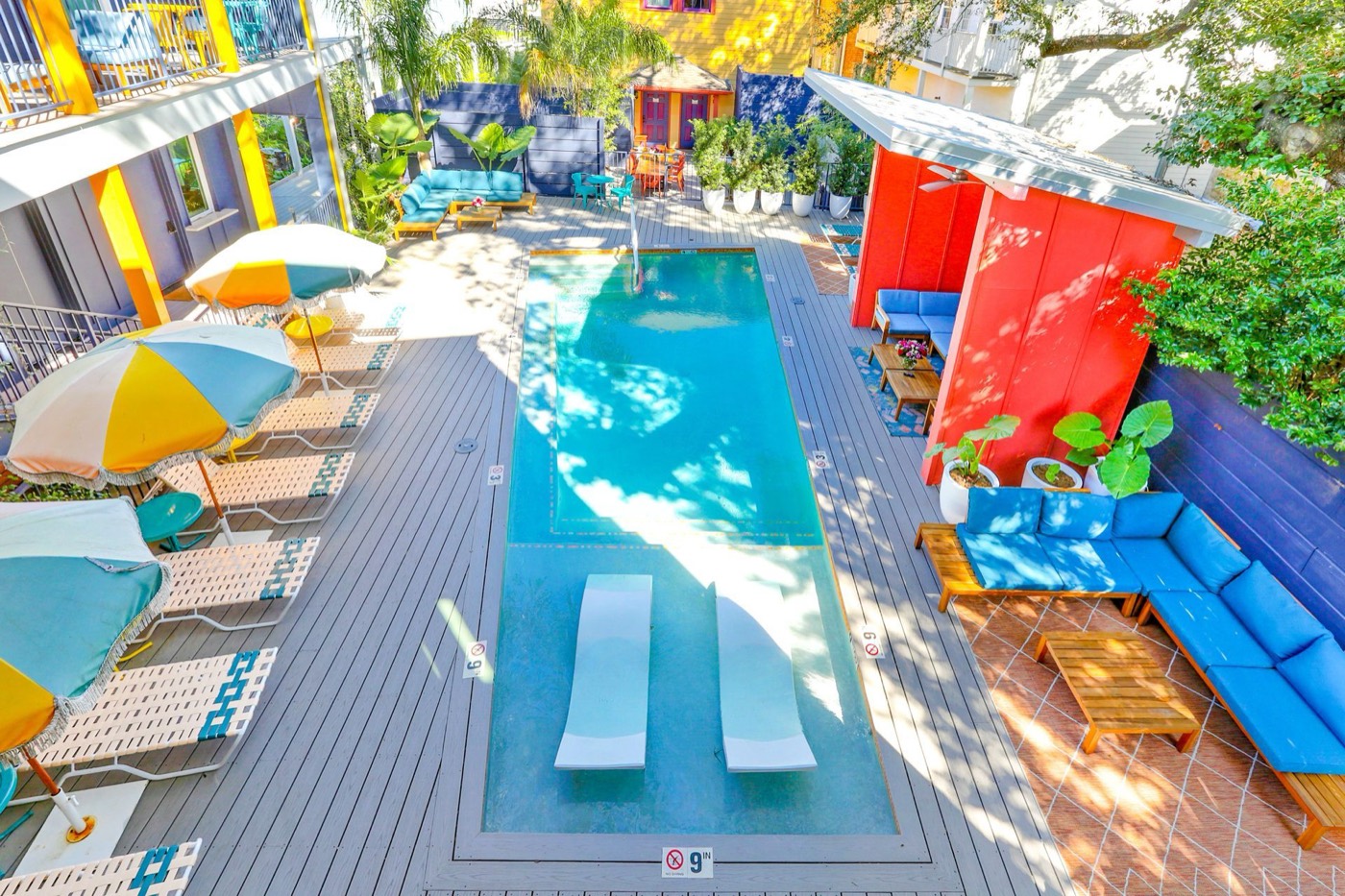 Colorful courtyard pool with umbrellas and loungers at The Syd in New Orleans, seen from above